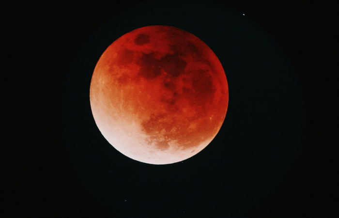 Reddish orange moon with black background.